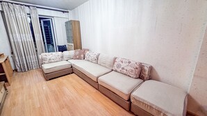 Un soggiorno con un divano componibile, pavimento in legno e un grande specchio.