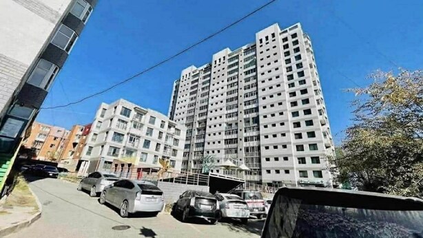 Un edificio residenziale a più piani con un parcheggio di fronte.
