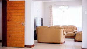 Una sala de estar con un sofá, un televisor y una puerta de madera.