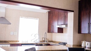 Una cocina con estufa, lavabo y armarios de madera.
