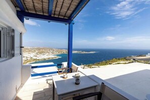 Eine Terrasse mit Tisch und Stühlen mit Blick auf die Küste.
