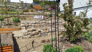 A garden with stone walls, a wooden bench, and various plants.