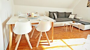A modern living space with a dining area, a sofa, and a small table.