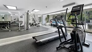 A gym with treadmills, weight machines, and a mirrored wall. - Main Downtown-Deluxe Suite w Pool, Gym & Balcony (Winnipeg)