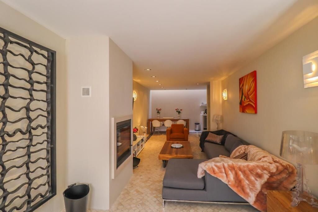 Un salon moderne avec un canapé, une table basse et, au fond, un coin repas.