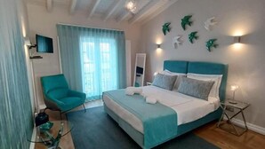 A modern bedroom with a bed, a chair, a mirror, and decorative wall art. - Villa Zawaia B&B Adults Only (Lagos)