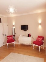 A room with a white dresser, a television, and two red chairs.