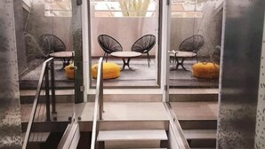 A modern staircase leading to a balcony with two chairs and a table, surrounded by glass walls. - Villa Zawaia B&B Adults Only (Lagos)