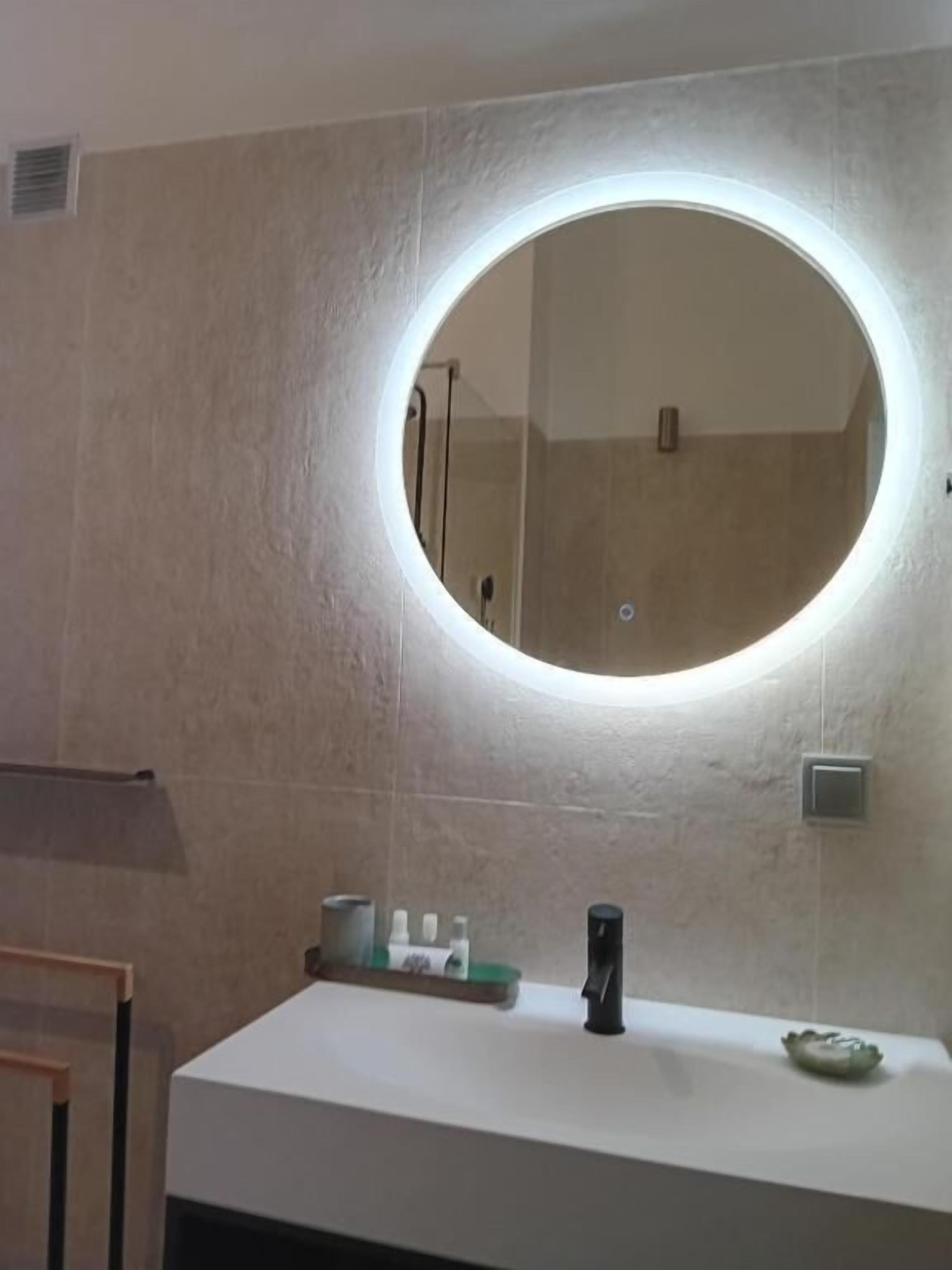 A bathroom with a round mirror, a white sink, and a towel rack.