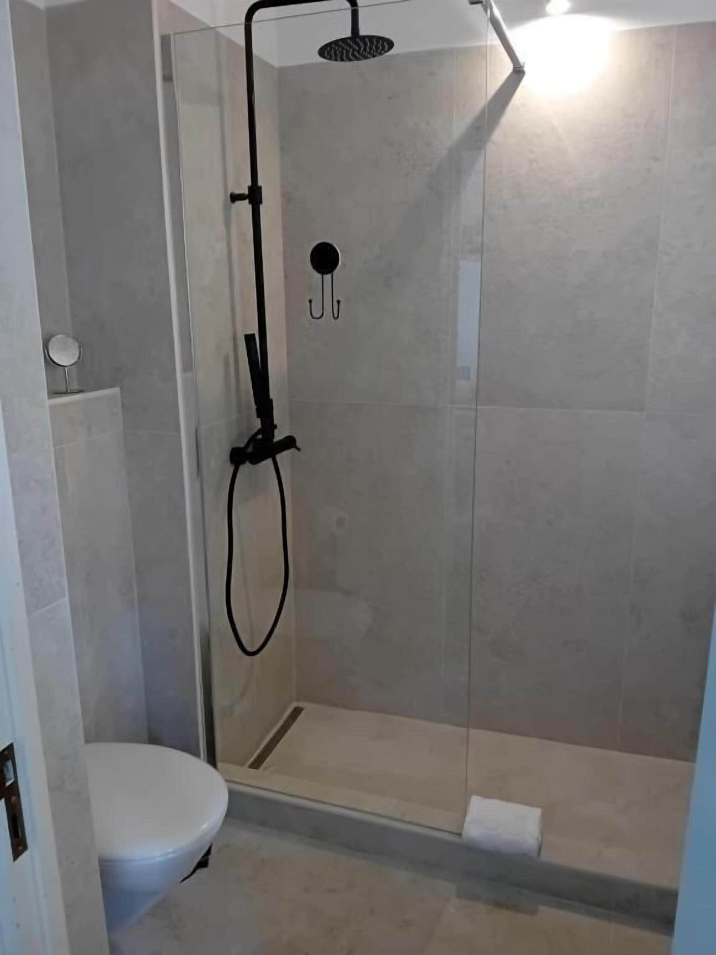 A shower with a glass enclosure, a toilet, and a wall-mounted towel rack.