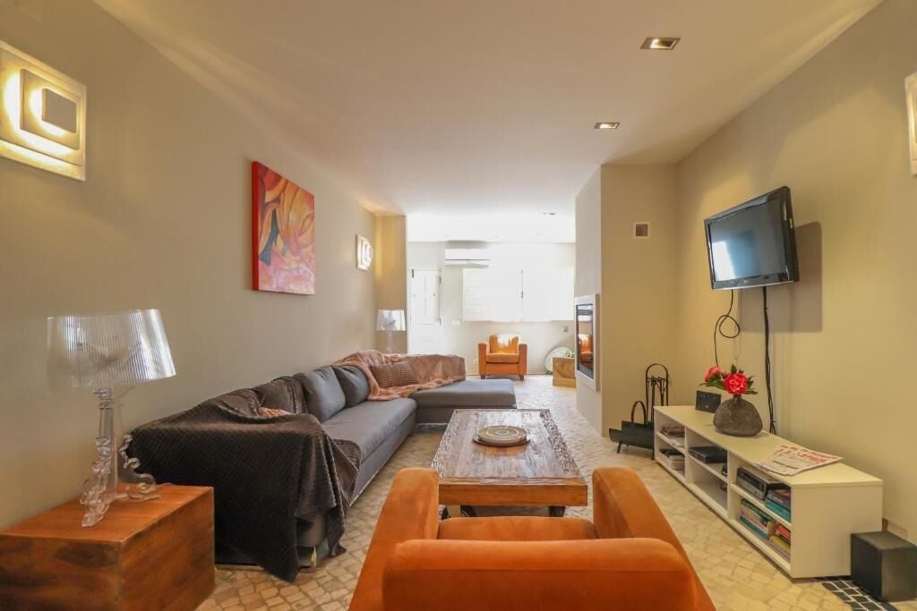 A modern living room with a sofa, coffee table, and orange chairs.