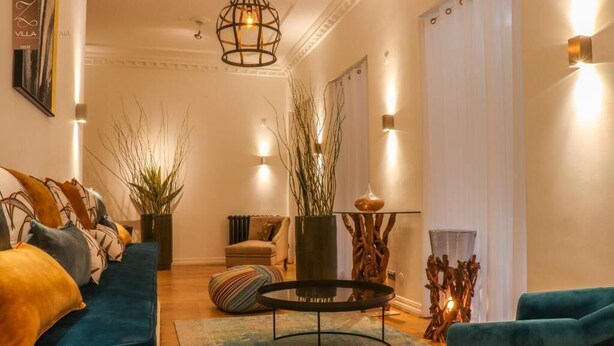 A living room with a sofa, a coffee table, and decorative plants. - Villa Zawaia B&B Adults Only (Lagos)
