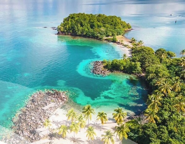 A tropical island with clear turquoise waters, lush greenery, and a small rocky beach area. - Studio Ti'Kay - Terrace 4 pers, 3mn from Anse Mitan beach (Les Trois-Îlets)