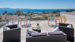 Eine Terrasse mit Korbmöbeln, einem Tisch mit Snacks und Blick aufs Meer.