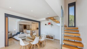 Ein modernes Interieur mit Essbereich, Küche und Treppe.