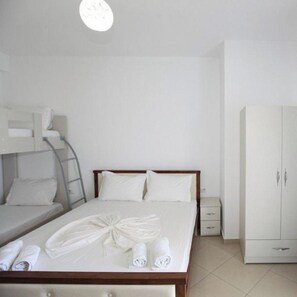 A single bed with a wooden headboard, a nightstand, a wardrobe, and a bunk bed to the left. - Vila Noah (Ksamil)