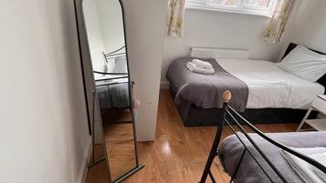 A bedroom with a bed, a dresser, a mirror, and a window with curtains.