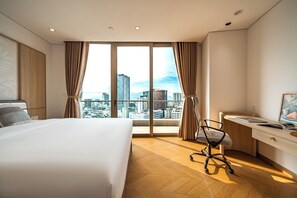 Una habitación de hotel moderna con una cama grande, un escritorio y vistas a la ciudad.