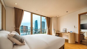 Una camera d'albergo moderna con un ampio letto, una scrivania e vista sullo skyline cittadino.