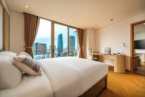 A modern hotel room with a large bed, a desk, and a view of the city skyline. - One-bedroom apartment with river and city views, located in the heart of city (Đà Nẵng)