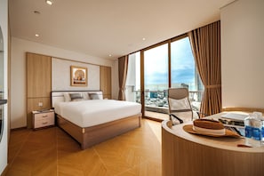A modern hotel room with a large bed, a desk with a laptop, a view of the city, and a large window with curtains. - One-bedroom apartment with river and city views, located in the heart of city (Đà Nẵng)