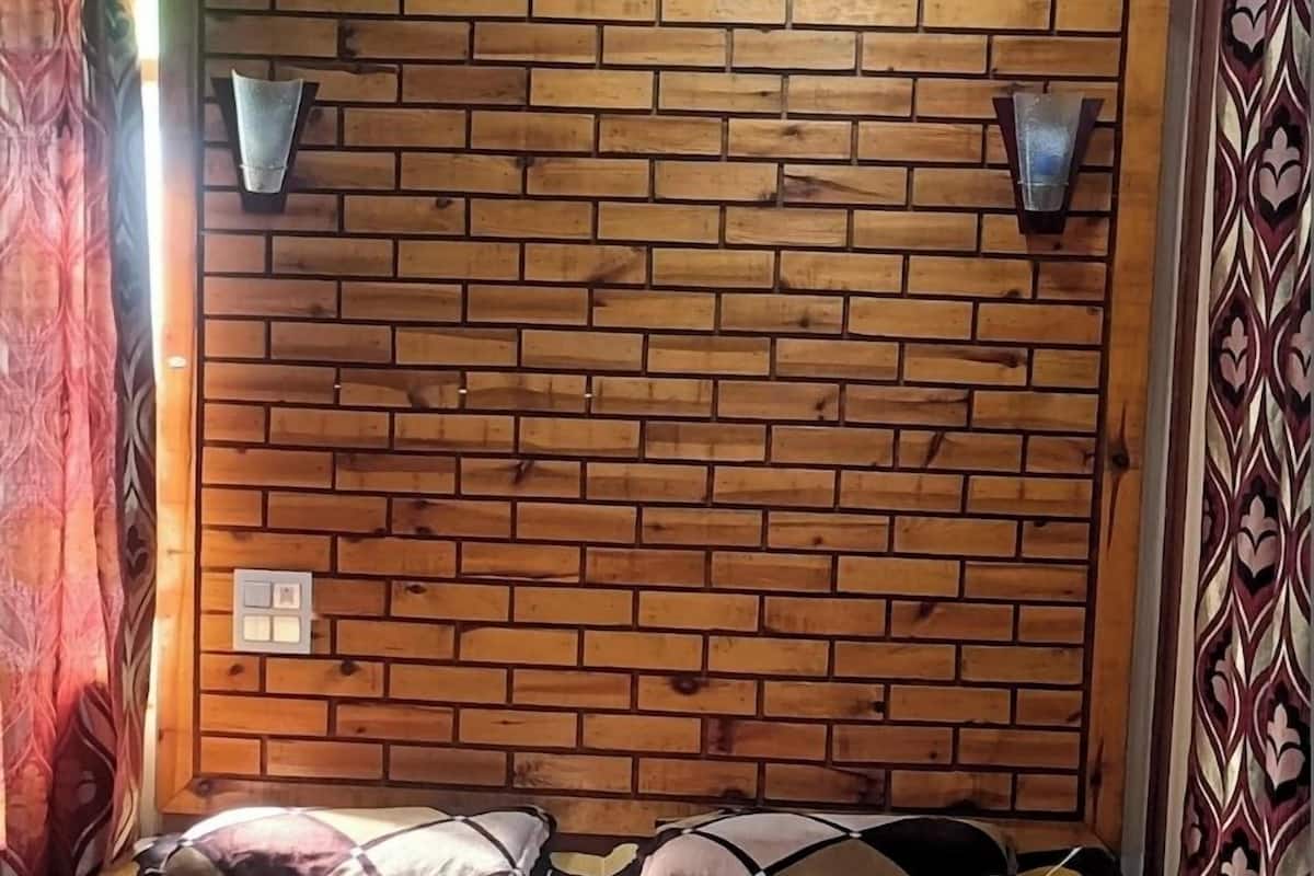 A bed with a brick-patterned headboard, two wall-mounted lights, and a floral-patterned bedspread.