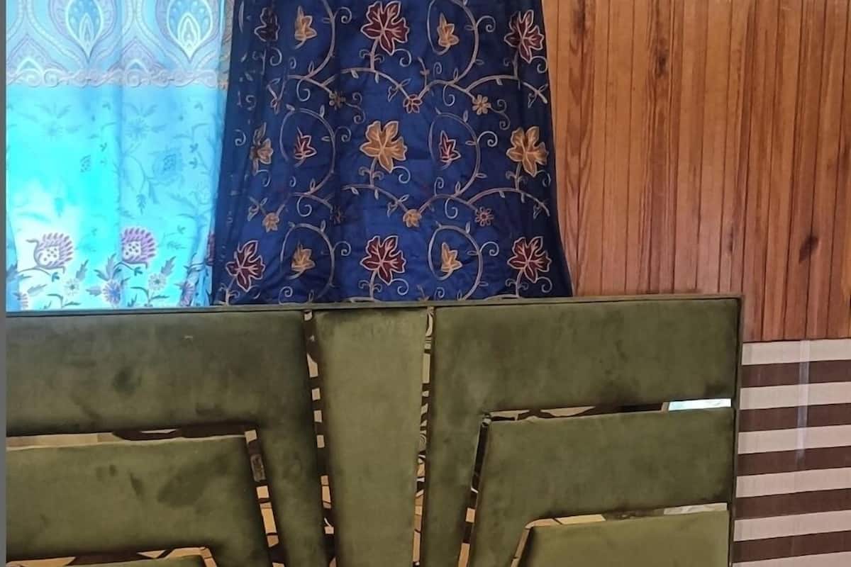 A bed with a checkered bedspread, a green upholstered headboard, and patterned curtains.