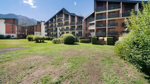 Ein mehrstöckiges Hotel mit Balkonen, einem gepflegten Rasen und einer Bergkulisse.