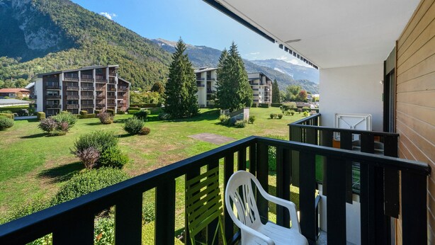 Ein Balkon mit Blick auf eine Berglandschaft, ein Gebäude mit mehreren Balkonen und ein Stuhl.
