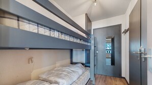 Ein Zimmer mit Etagenbetten, einer Tür und einer Leuchte.