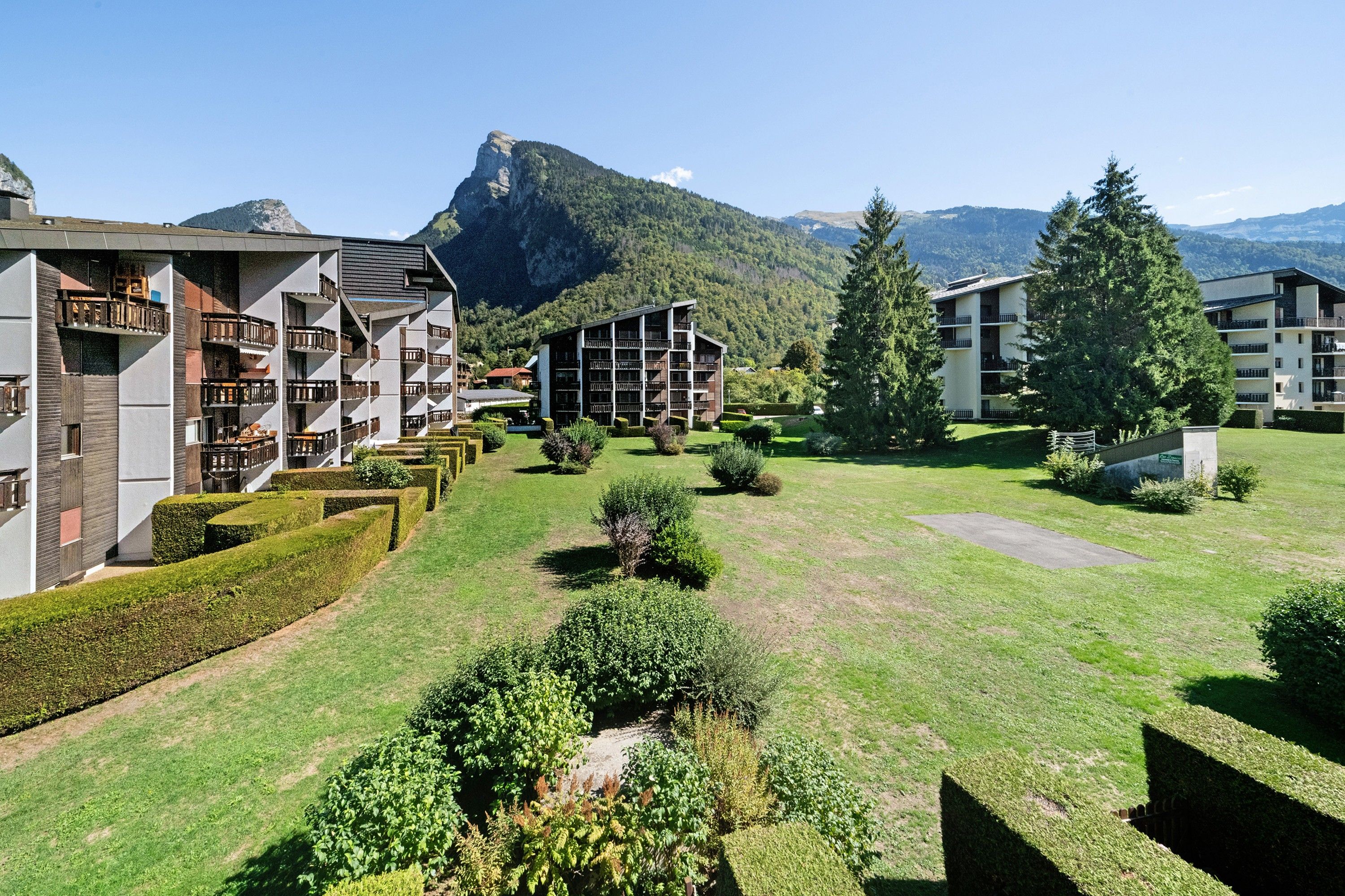 Un hôtel composé de plusieurs bâtiments, doté d’une pelouse bien entretenue et surplombant une montagne.