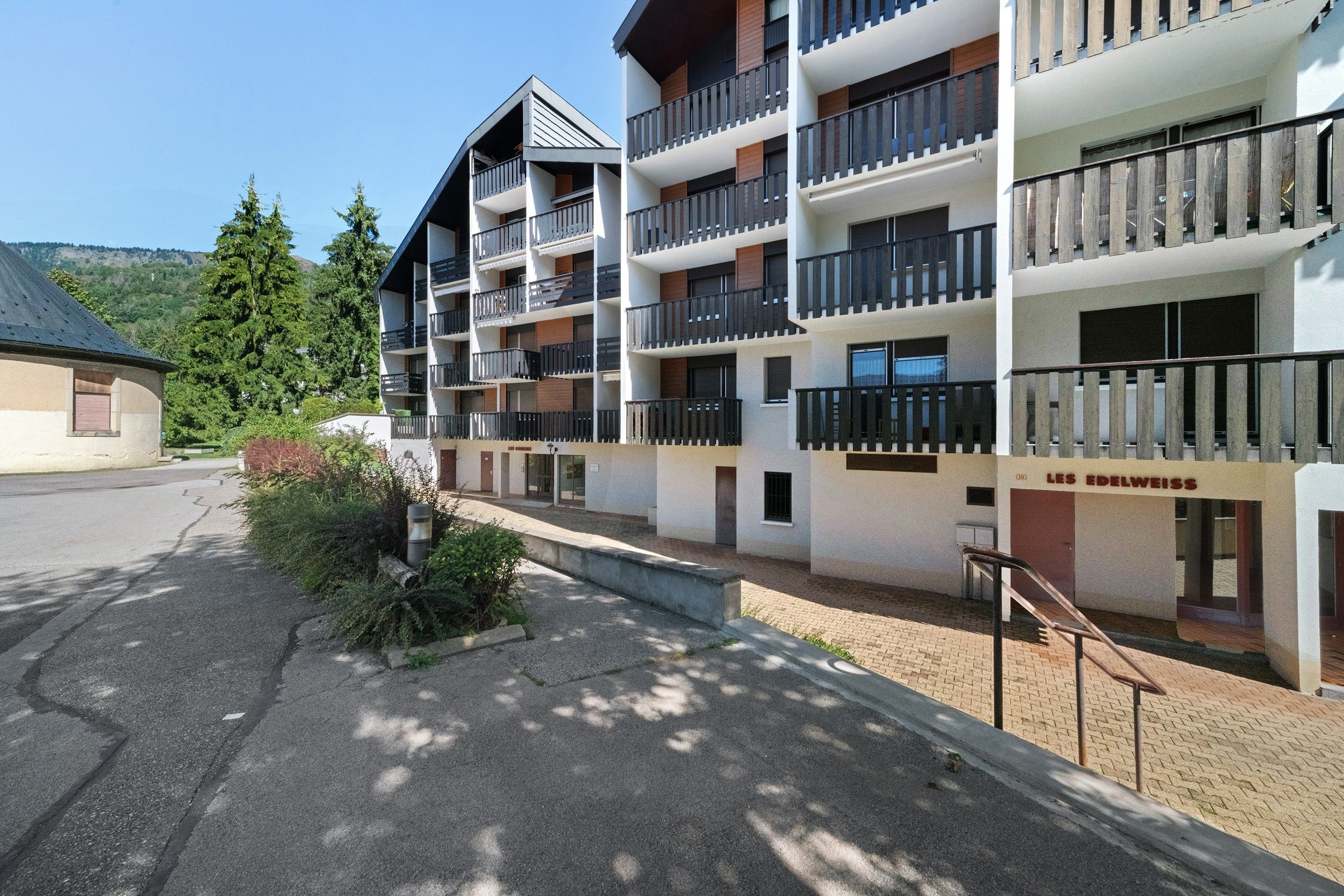 Ein mehrstöckiges Hotel mit Balkonen, einem Parkplatz und einem Schild mit der Aufschrift 'LES EDELWEISS'.