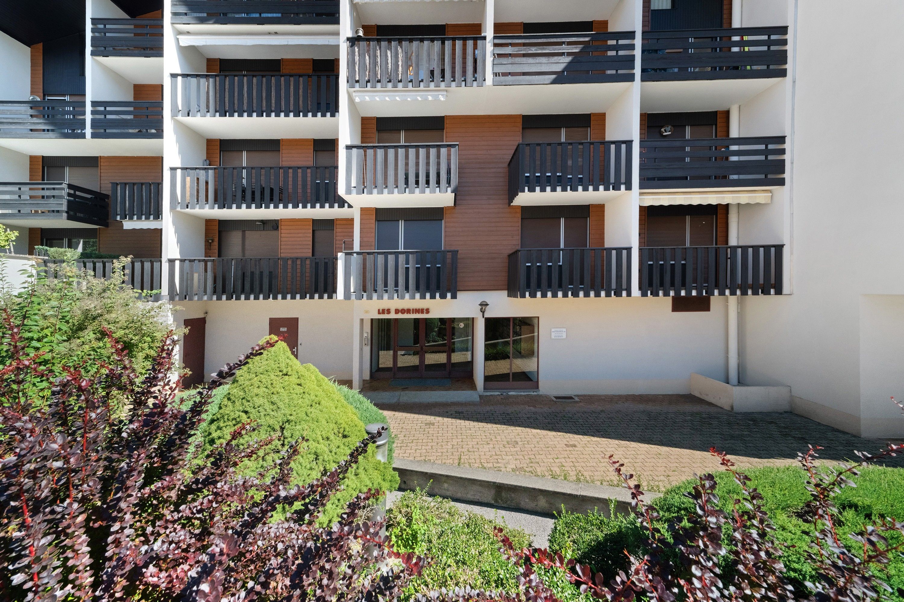 Un immeuble résidentiel à plusieurs étages, doté de balcons, d’une entrée sécurisée et d’une cour aménagée.