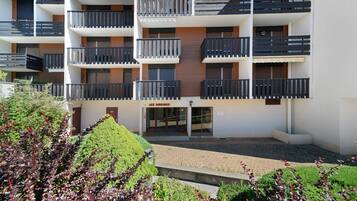 Un immeuble résidentiel à plusieurs étages, doté de balcons, d’une entrée sécurisée et d’une cour aménagée.