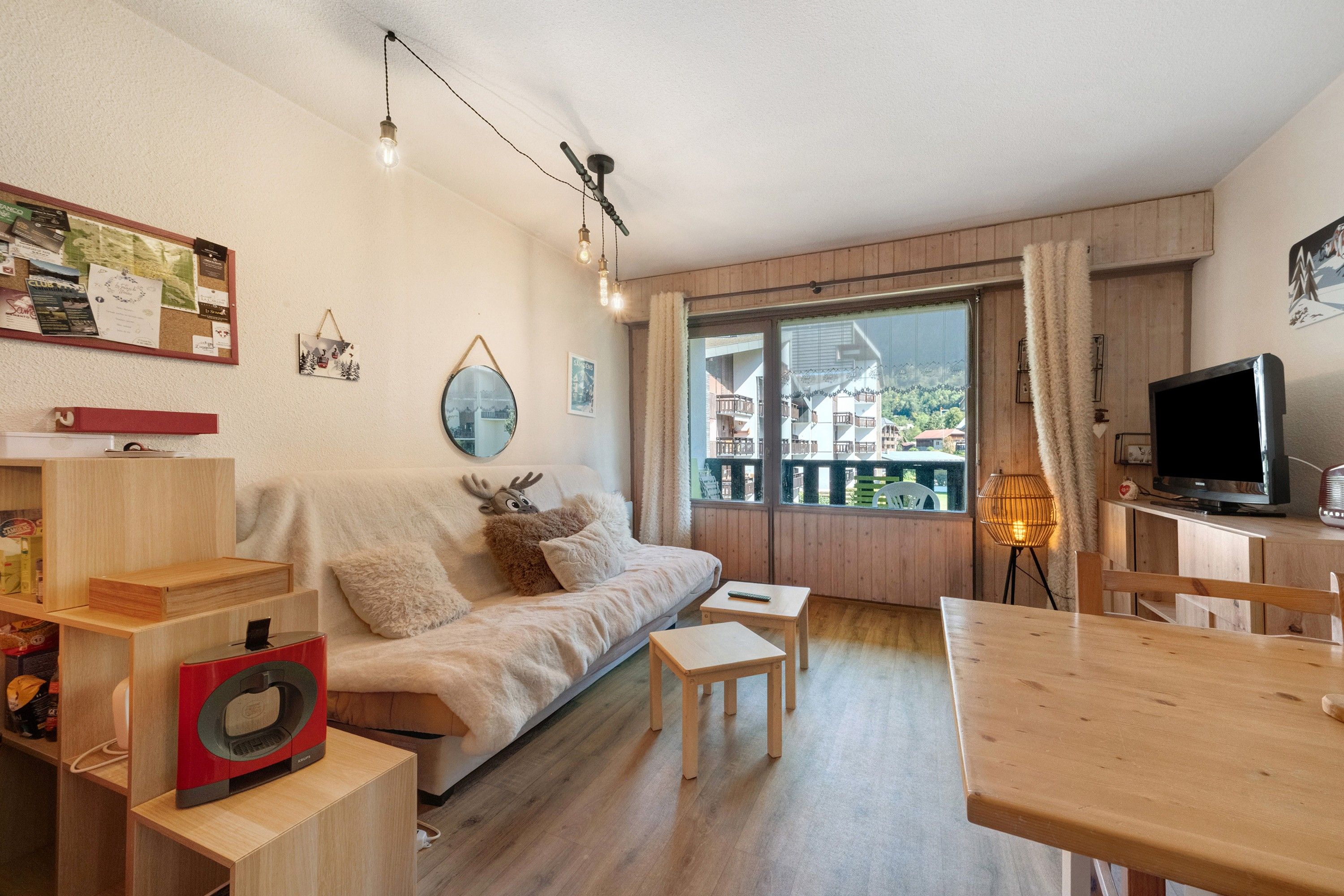 Un salon chaleureux avec un canapé, une table basse, un téléviseur et une table à manger en bois.