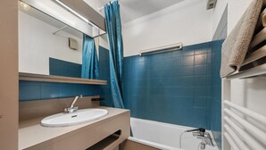 Ein Badezimmer mit einem weißen Waschbecken, einem Spiegel, einem Handtuchhalter und einer Badewanne.
