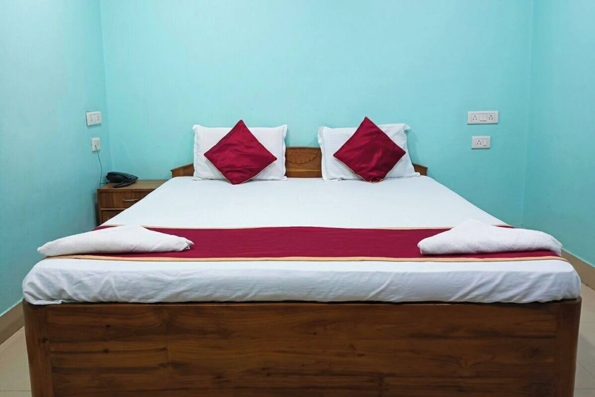 Ein Bett mit hölzernem Gestell, weißer Bettwäsche und roten Kissen.