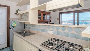 A kitchen with a gas stove, a sink, and a window overlooking a scenic view. - Holiday Home 'Mariella' with Sea View and Private Terrace (Palau)