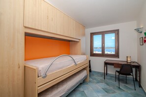 Een slaapkamer met een stapelbed, een bureau en een stoel.