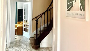 Eine Treppe mit dunkler Geländer und weißen Wänden, die zu einem Zimmer mit Bett und Fenster führt.