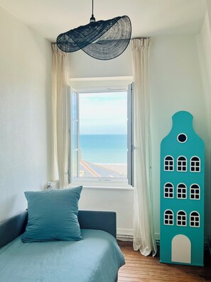 Un dormitorio con cama, vista al mar a través de una ventana y un adorno en la pared.