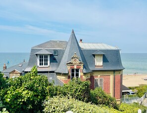 A coastal house with a steep roof, a small balcony, and a view of the beach. - An Exceptional Seaside Getaway with Breathtaking Views (3-Star Villa) (Villers-sur-Mer)