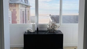 Ein Zimmer mit großem Fenster, einem schwarzen Tisch und einem Schiffmodell.