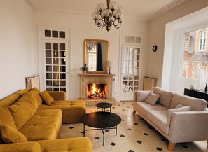 A living room with a fireplace, two sofas, a coffee table, and a chandelier. - An Exceptional Seaside Getaway with Breathtaking Views (3-Star Villa) (Villers-sur-Mer)
