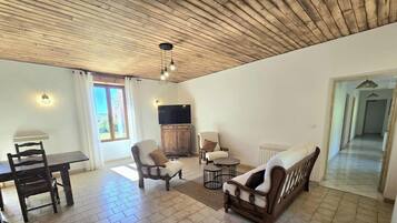 Un salon avec un plafond en bois, un téléviseur, une table à manger avec des chaises et un canapé.