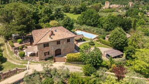 A stone building with a tiled roof, a swimming pool, and a surrounding garden. - Villa Raggio di Luce Stigliano (Sovicille)
