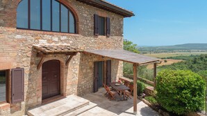 A stone house with a patio, a table, and chairs. - Villa Raggio di Luce Stigliano (Sovicille)