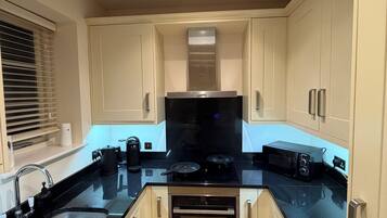 A modern kitchen with white cabinets, a black countertop, a built-in oven, and a microwave.