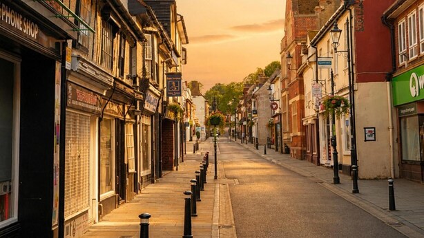 A street lined with buildings, including a shop with a sign that reads 'PHONE SHOP'. - Modern Cottage Sleeps 4 With Patio (Royston)