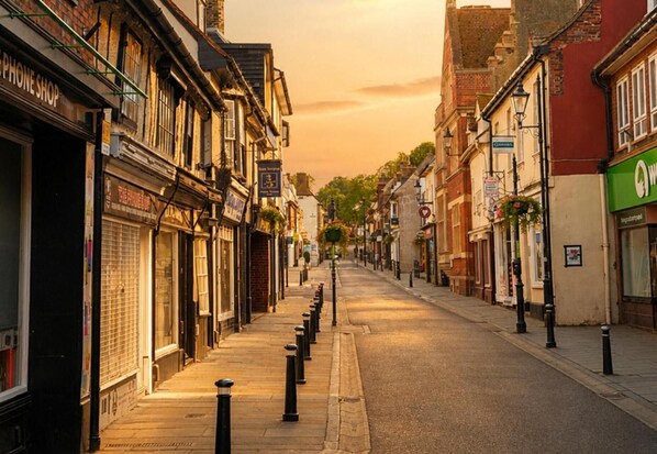 A street lined with buildings, including a shop with a sign that reads 'PHONE SHOP'. - Modern Cottage Sleeps 4 With Patio (Royston)